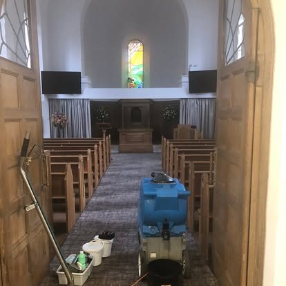The machine in the aisle of a chapel between wooden pews